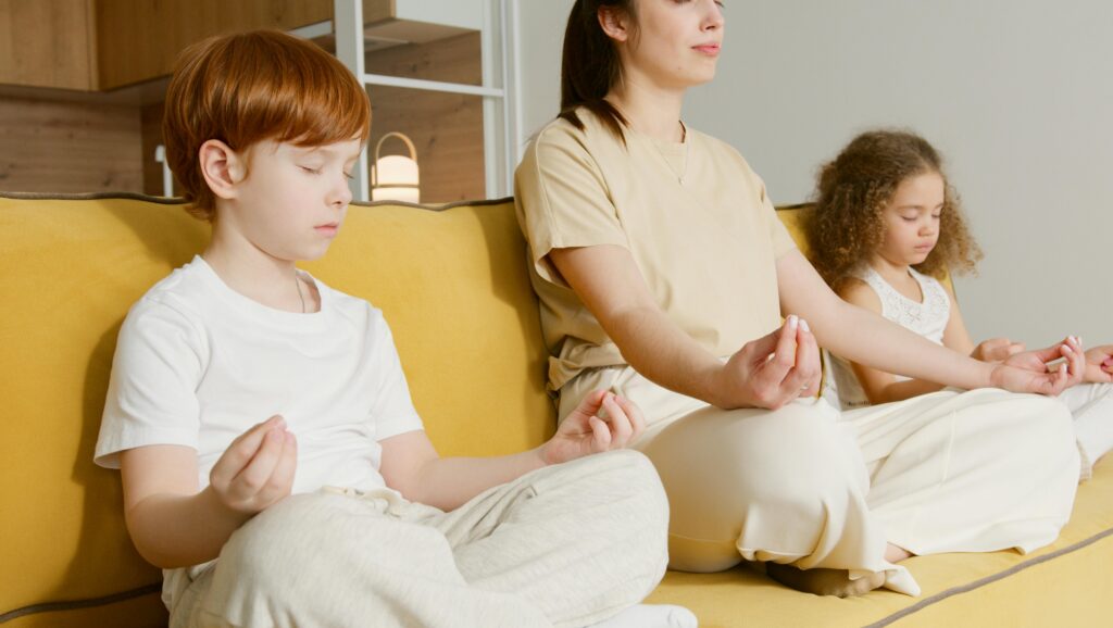 Family practicing meditation together on a couch, promoting mindfulness and relaxation.